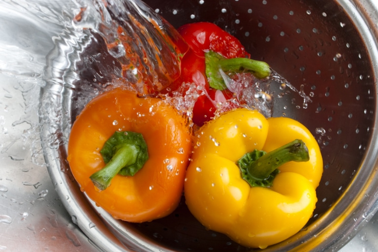 washing colorful peppers in colander